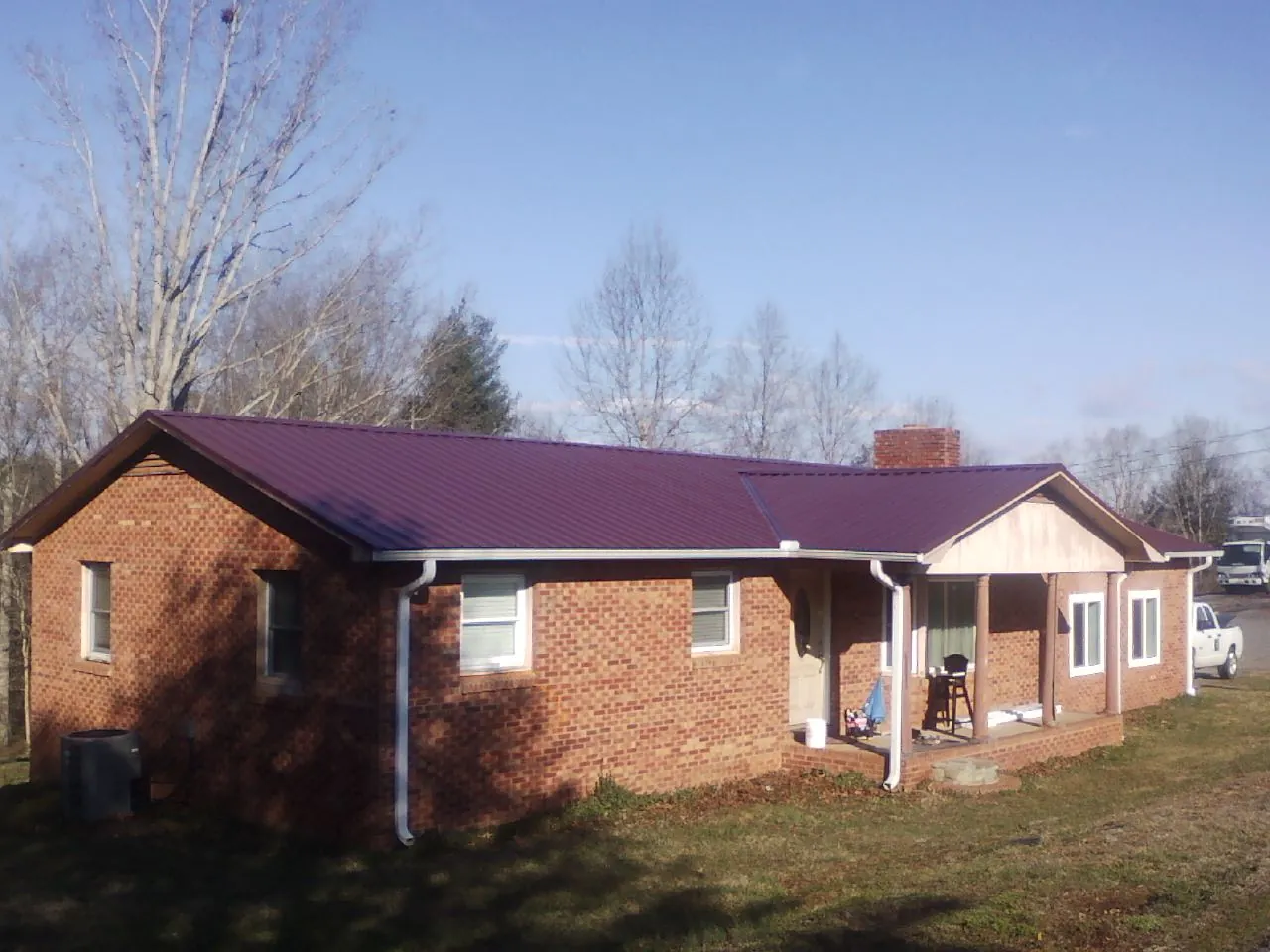 Burgundy metal roof on a brick ranch home with a new addition in Sweetwater