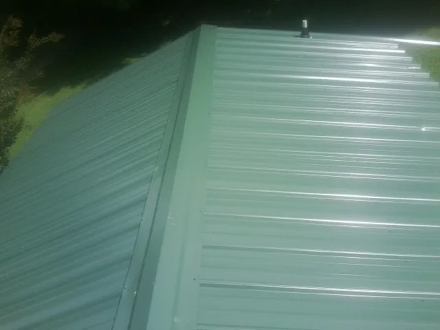 New green metal panels meeting at the ridge of a roof — Flat Roof Repair work by our crew in Sweetwater