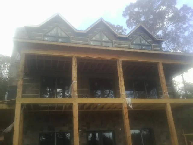 Dormers and porch framing on a large log home under construction — Roof Coating work by our crew in Sweetwater
