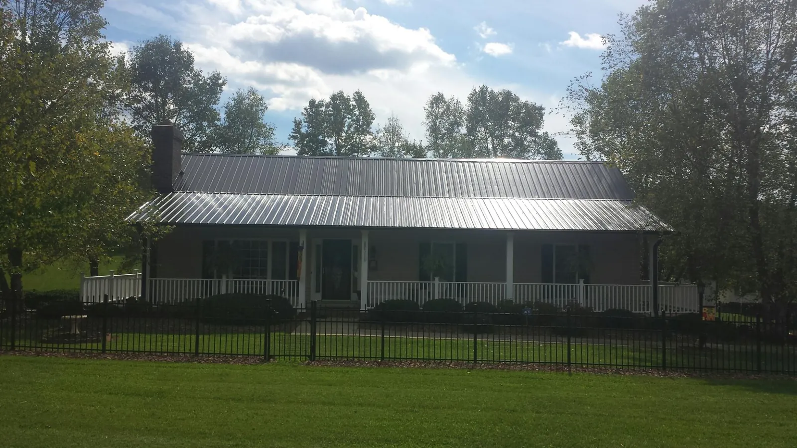 Gray metal roof on a brick ranch with a full width front porch — Gutter Guard Installation work by our crew in Sweetwater