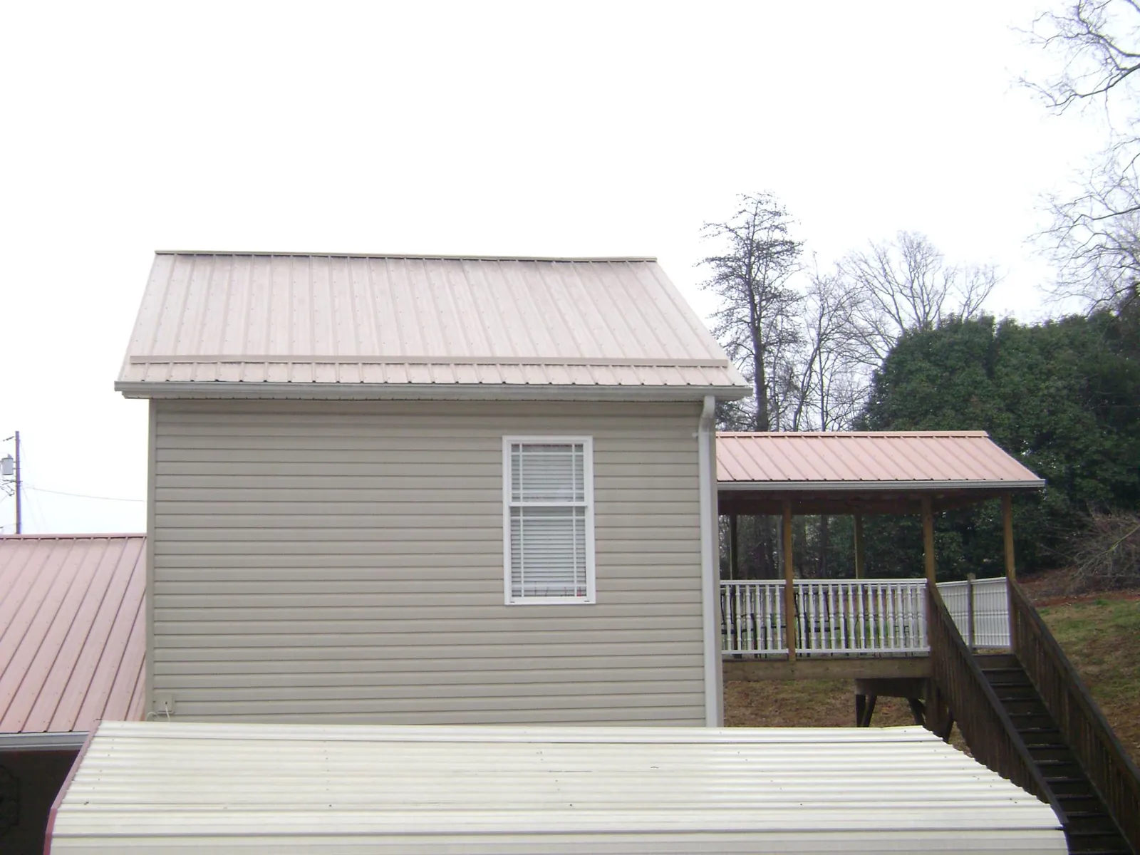Tan metal roofs on a two story addition and attached porch, from a Roof Replacement job in Sweetwater