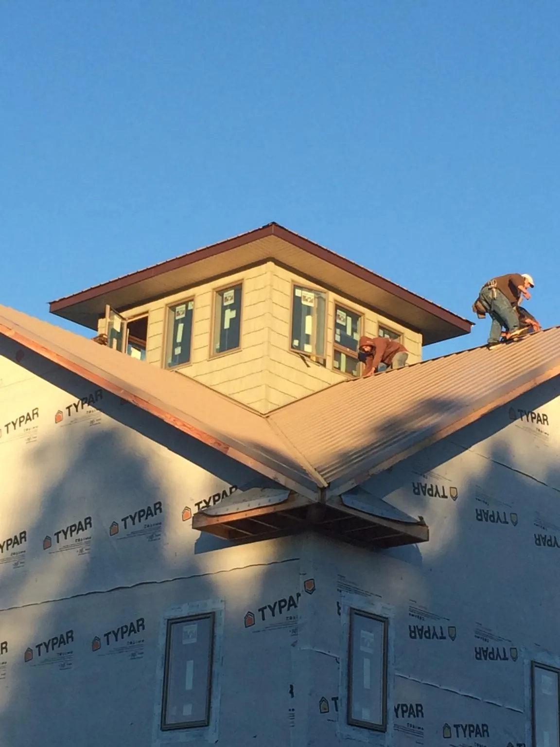 Roofers working around a rooftop cupola on a new metal roof at sunset — Roof Waterproofing in Sweetwater by Roofing Brothers